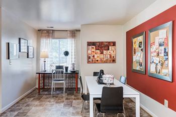 a dining room with a table and chairs and a red accent wall